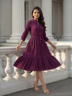 Woman in a purple dress standing in front of classical architecture