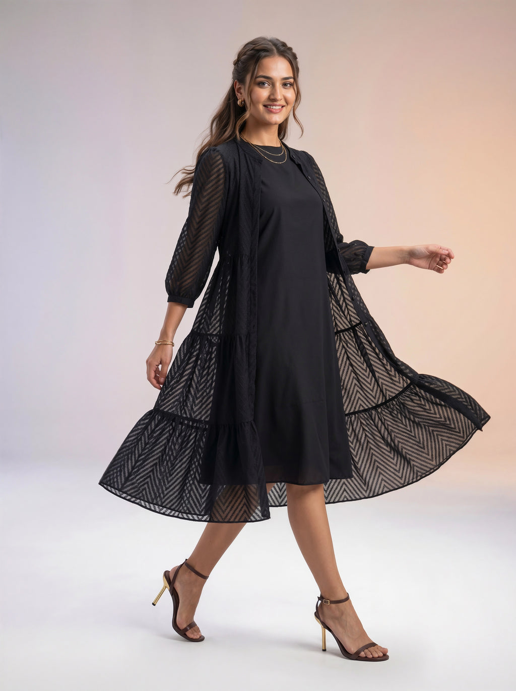 Woman wearing a black dress with sheer sleeves against a white background