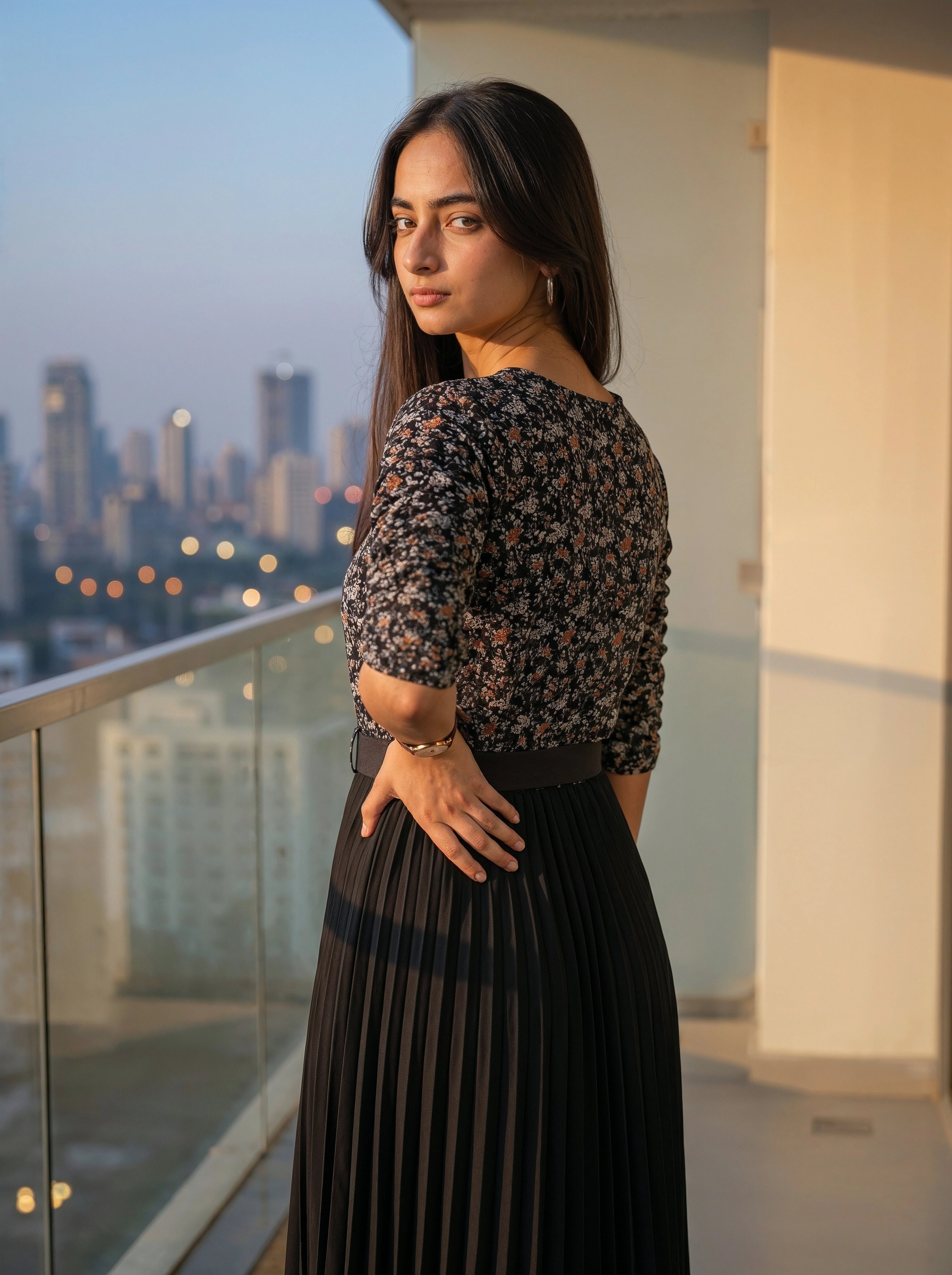 Woman standing on a balcony with a cityscape view at dusk
