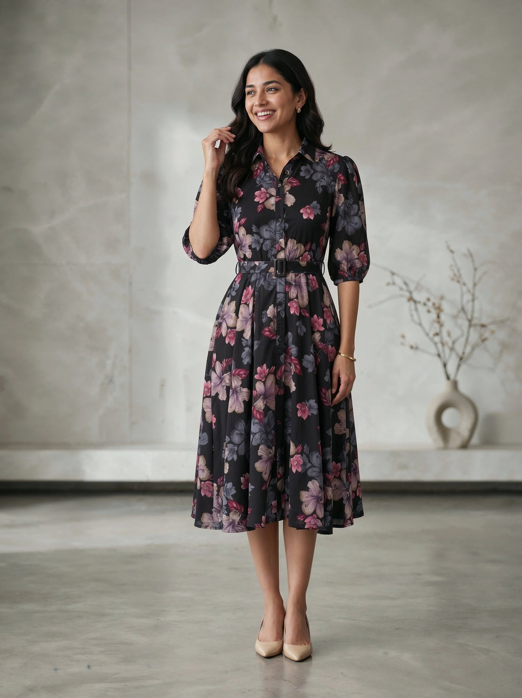 Woman wearing a floral dress standing in a room with a vase in the background