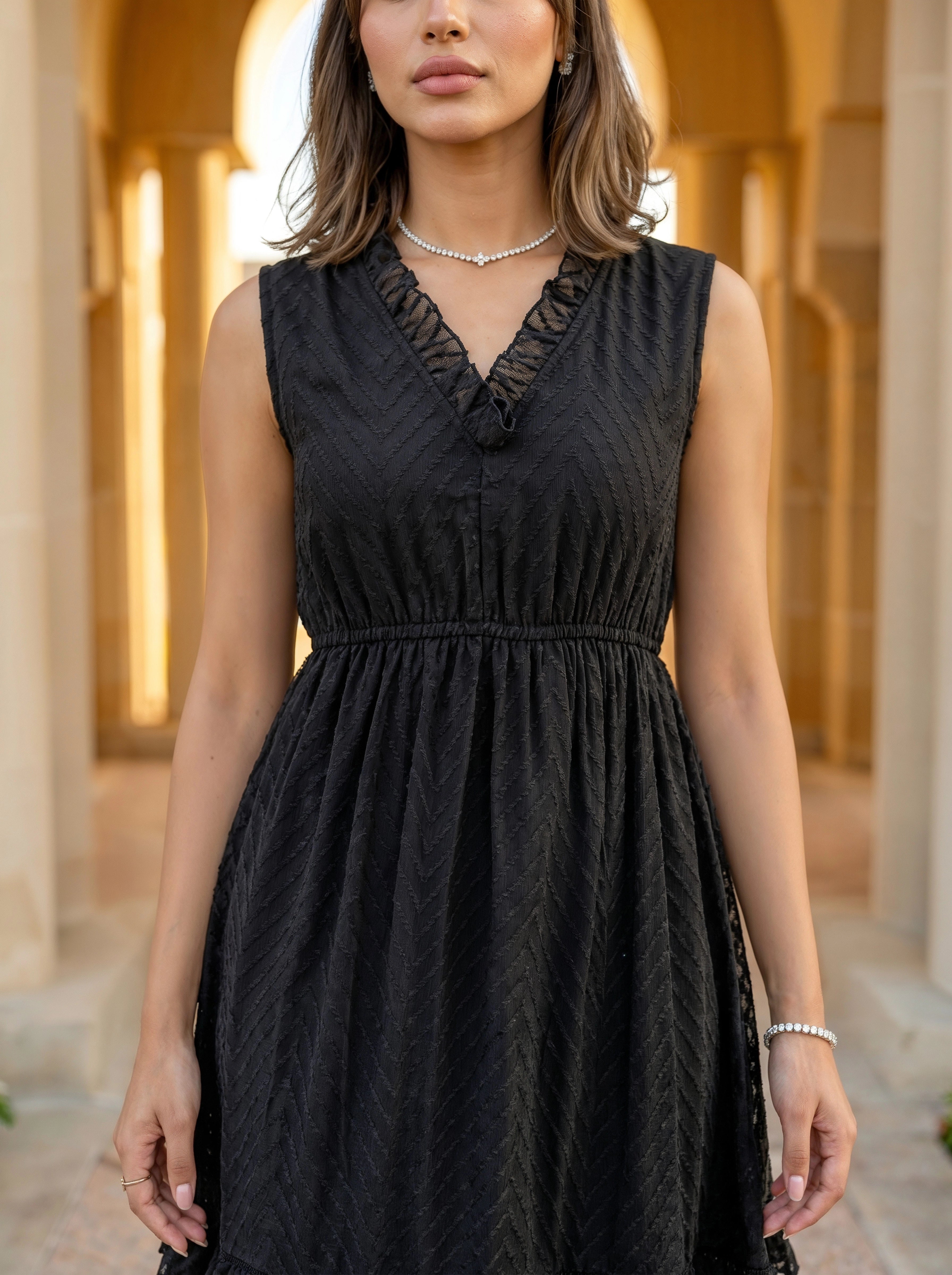 Woman wearing a black dress with intricate details in an outdoor setting