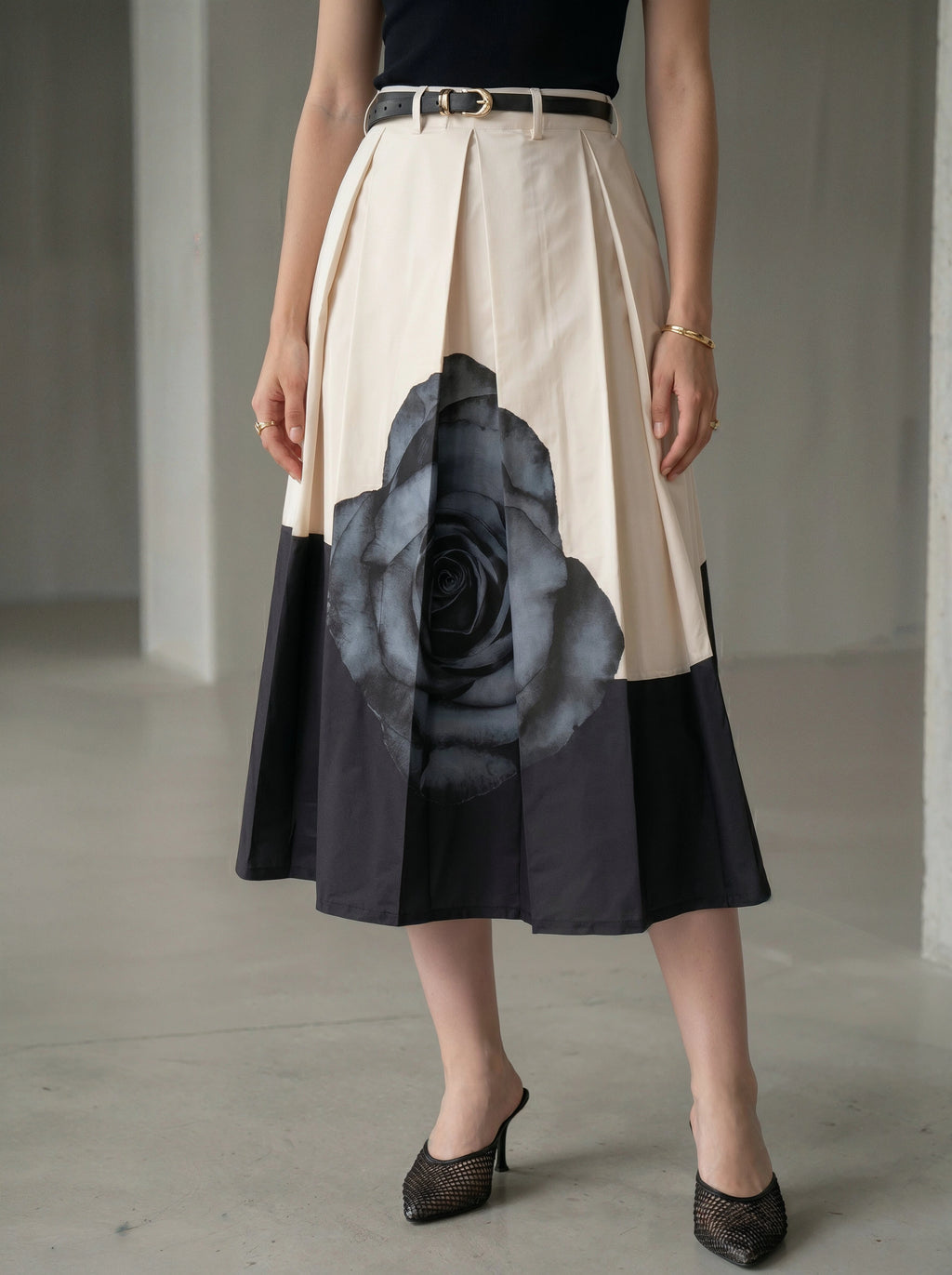 Woman wearing a skirt with a large black rose design on a plain background