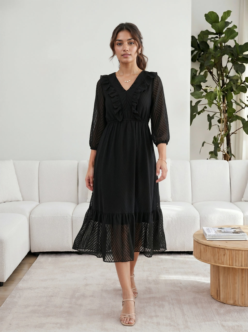 Woman wearing a black dress standing in a modern living room.