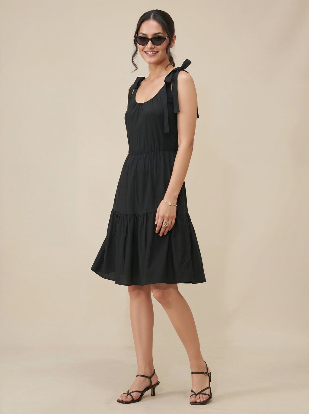 Woman wearing a black dress with bow straps against a beige background