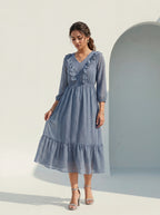 Woman wearing a blue dress standing against a light background