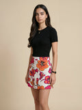 Woman wearing a black top and floral skirt on a beige background