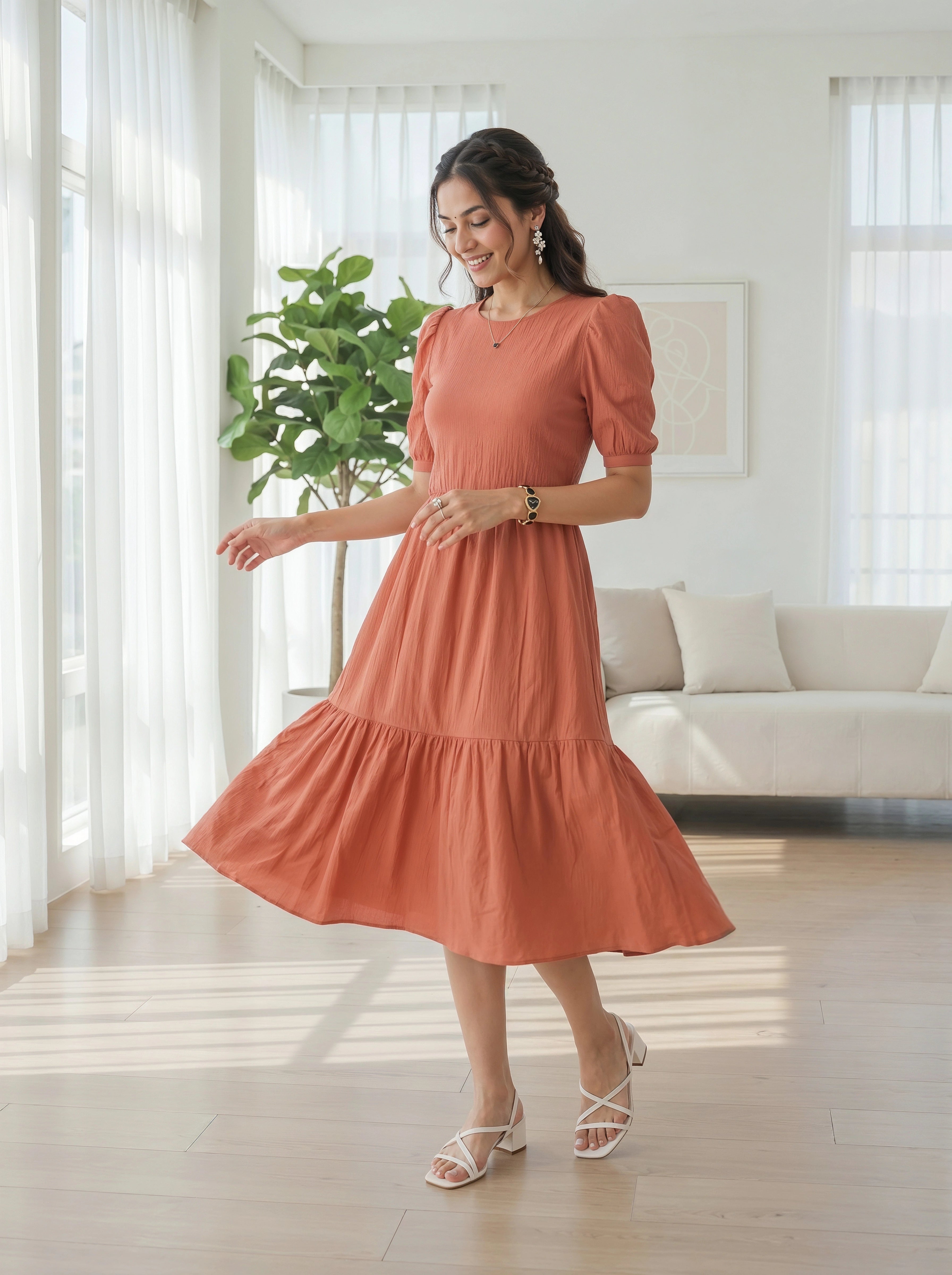 Woman in a coral dress standing in a bright living room.