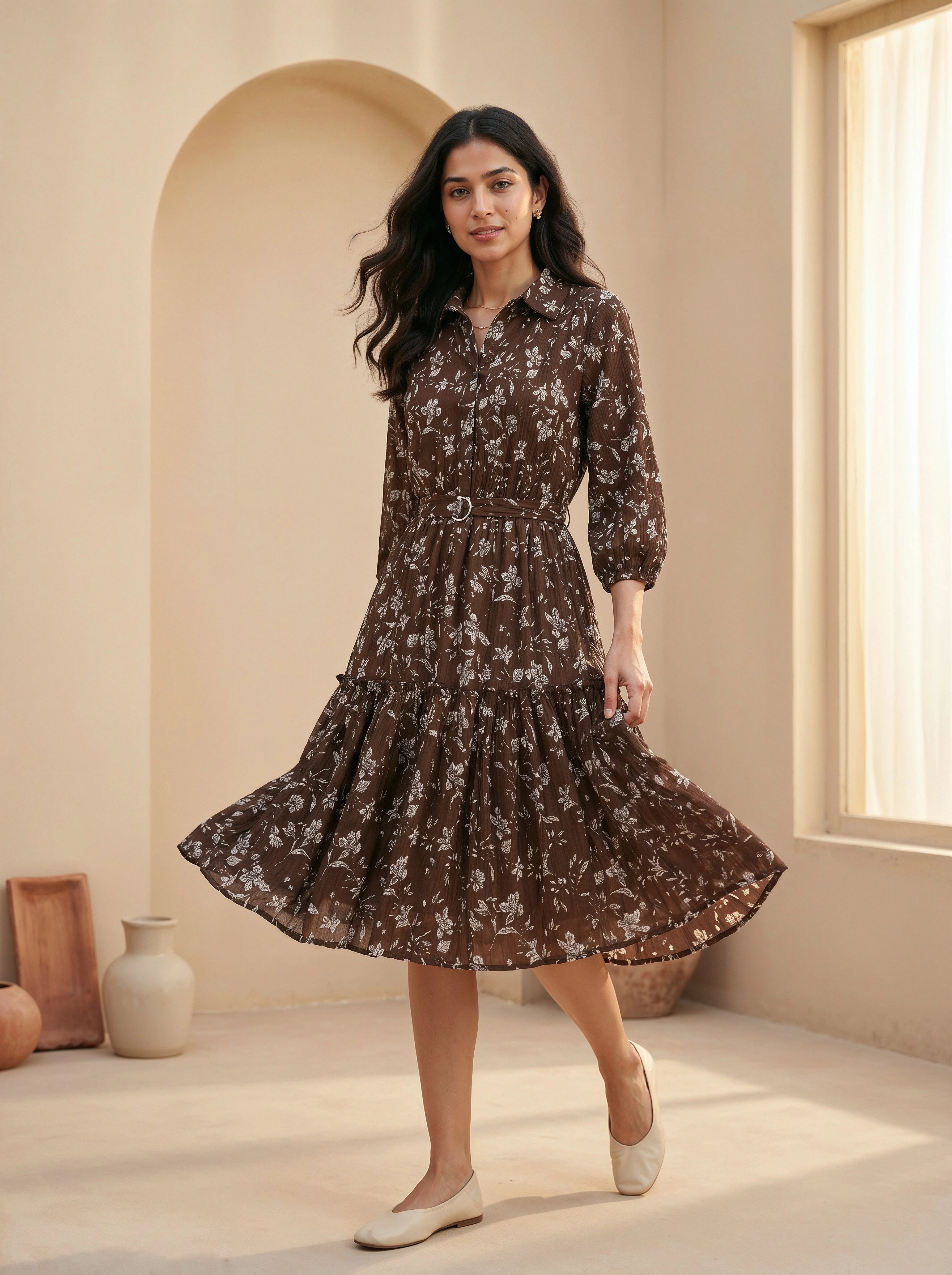 Woman wearing a brown floral dress in a bright room with natural light.