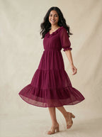 Woman wearing a burgundy dress with puff sleeves against a beige background
