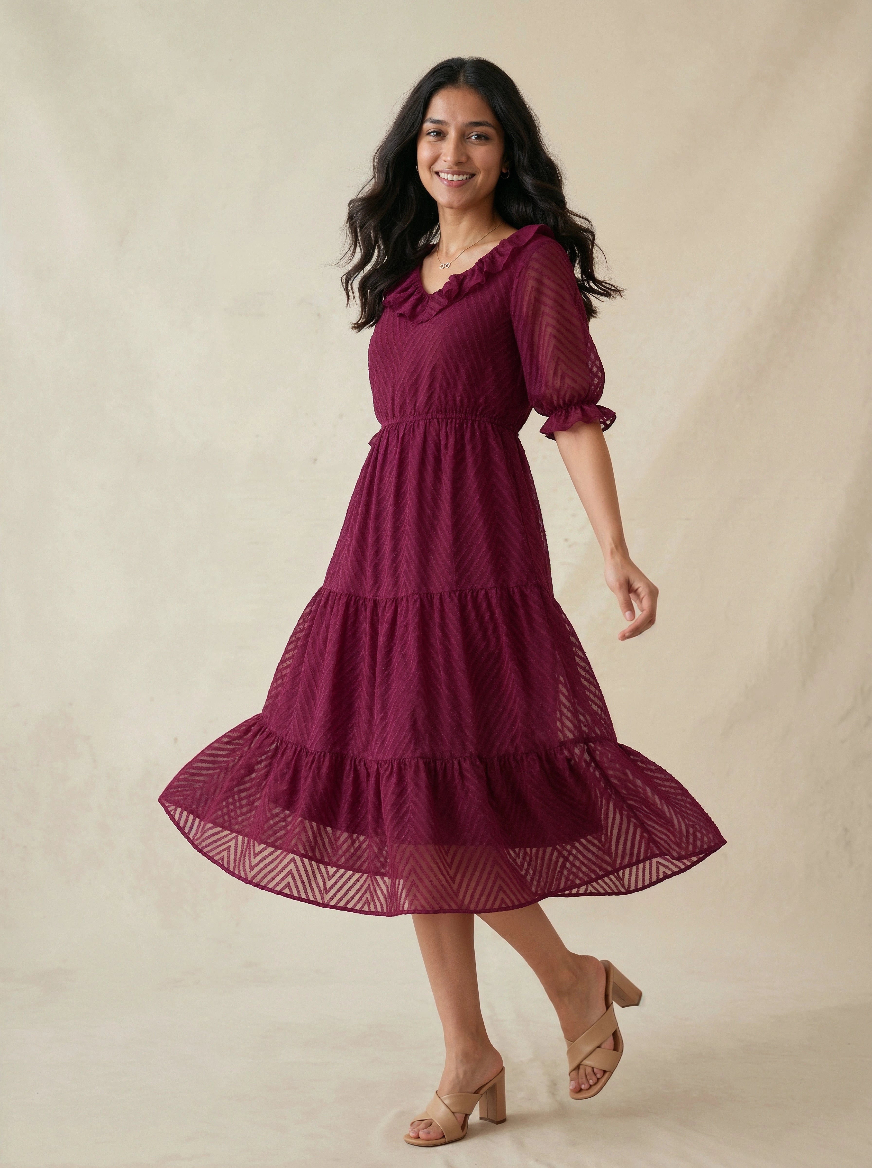 Woman wearing a burgundy dress with puff sleeves against a beige background