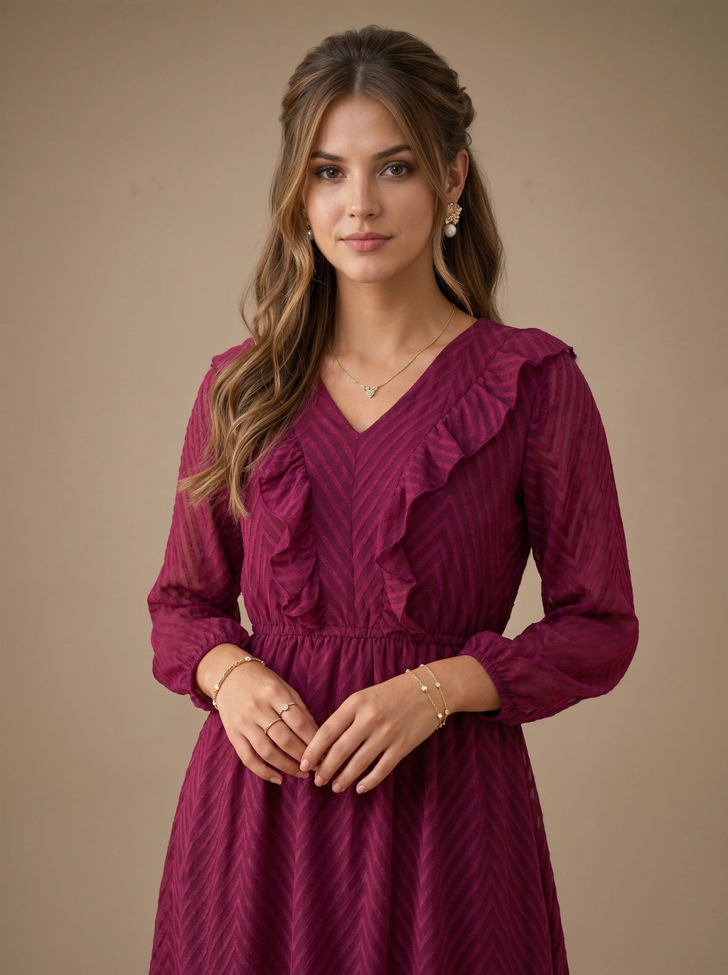 Woman wearing a burgundy dress with ruffled details against a beige background