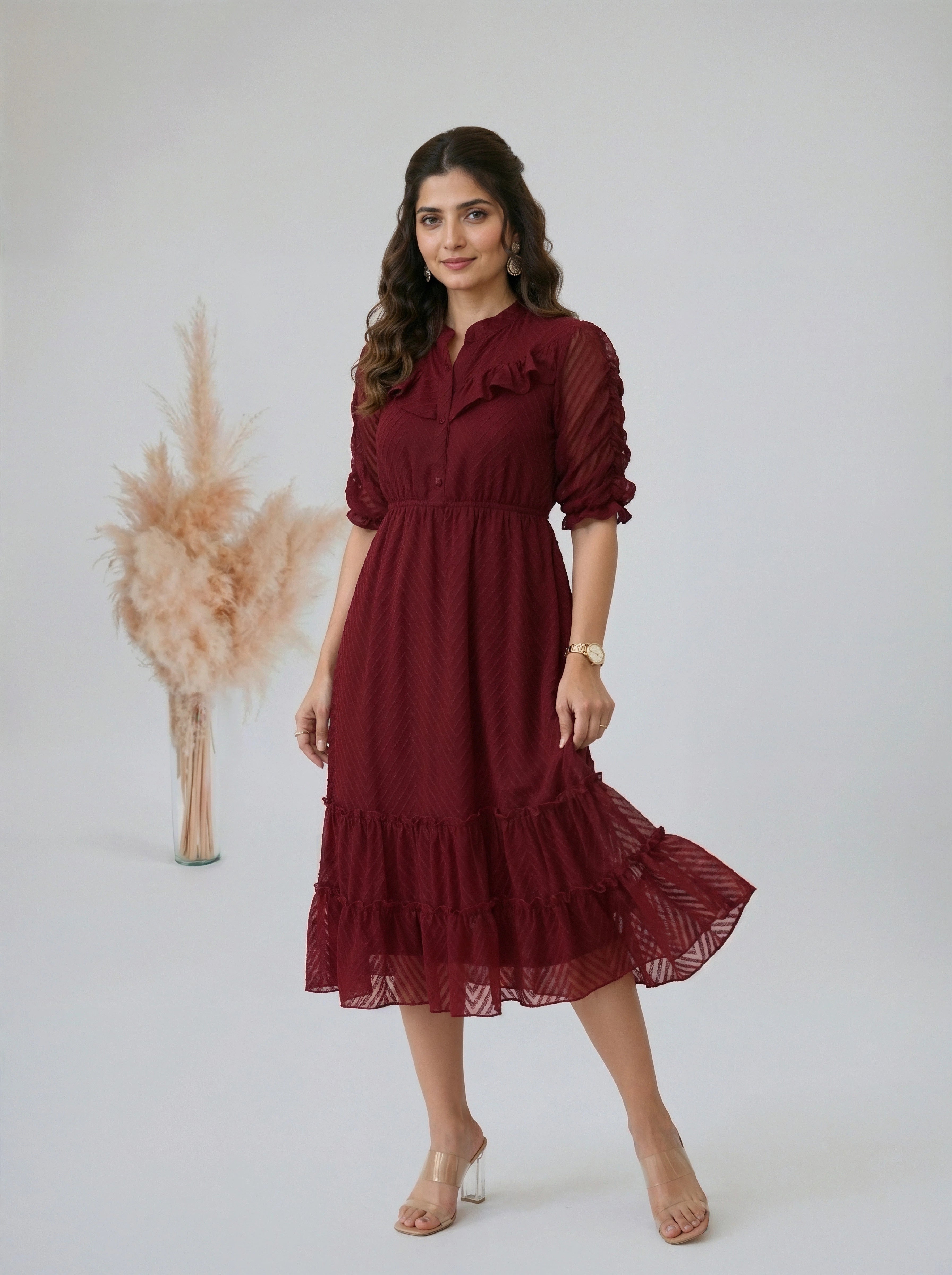 Woman wearing a burgundy tiered midi dress with ruffled details in a bright room