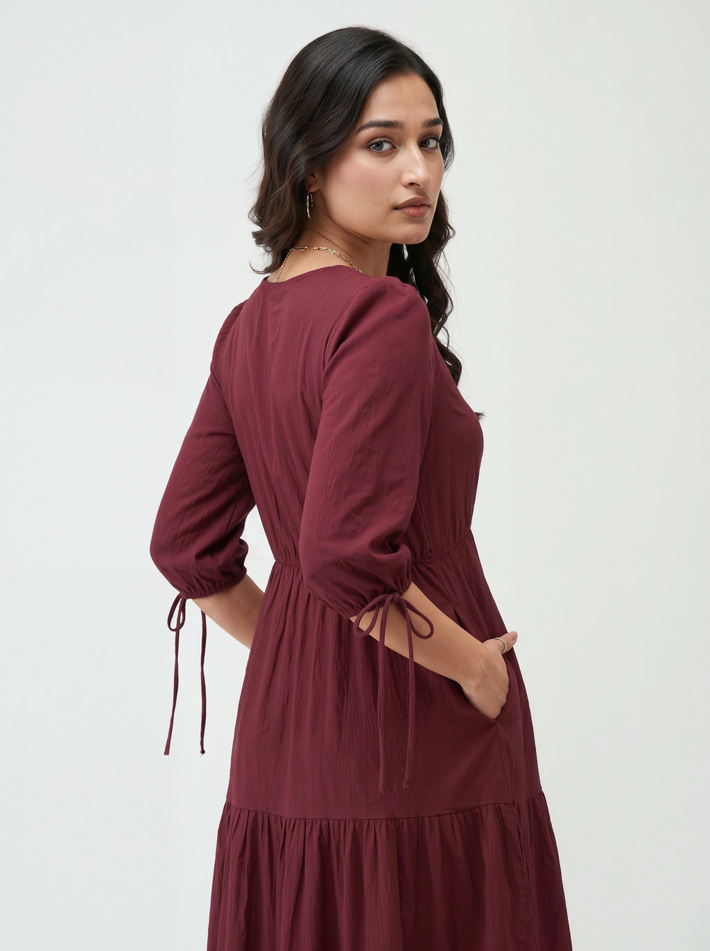 Woman wearing a burgundy dress with long sleeves on a white background