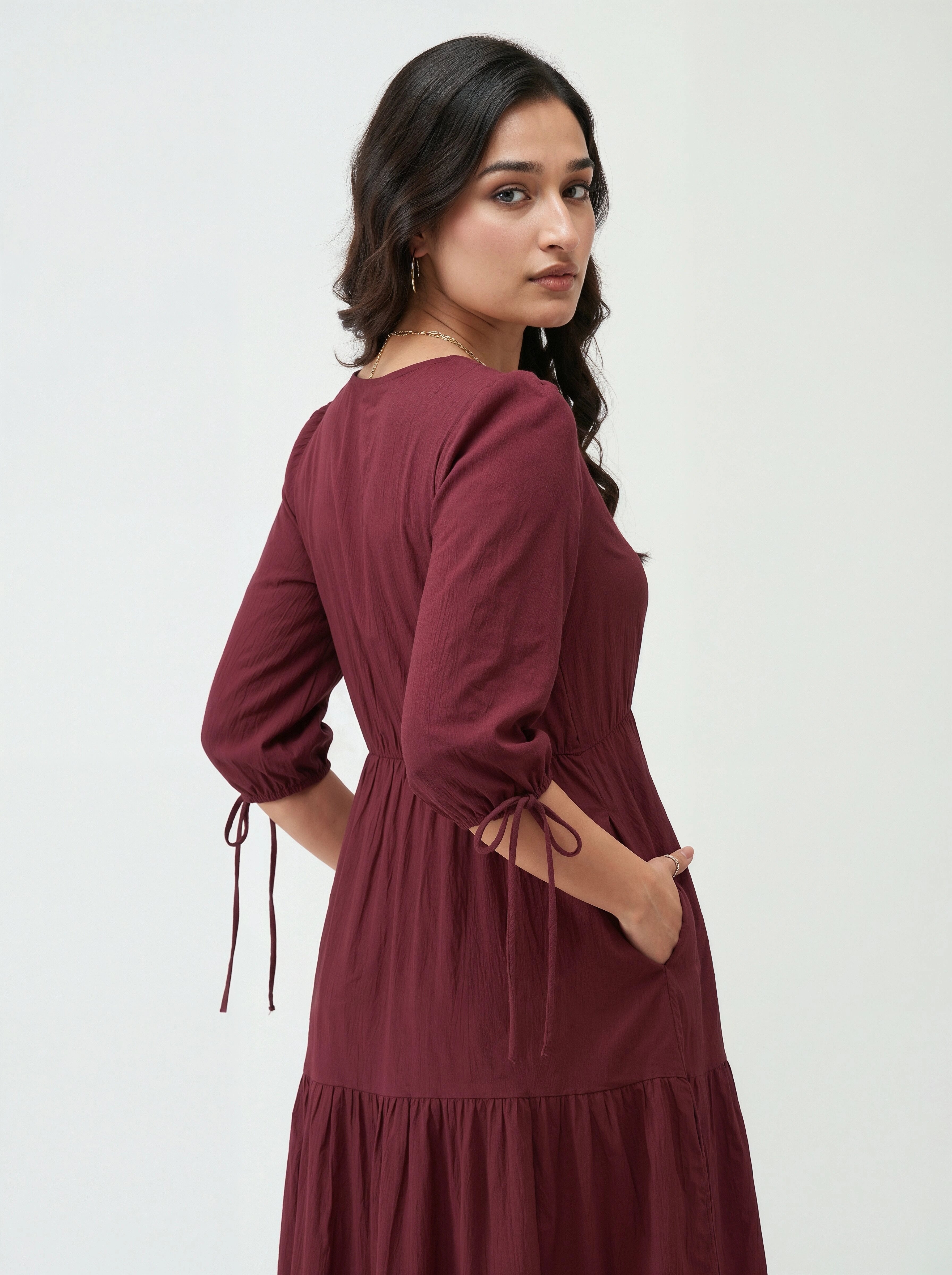 Woman wearing a burgundy dress with long sleeves on a white background