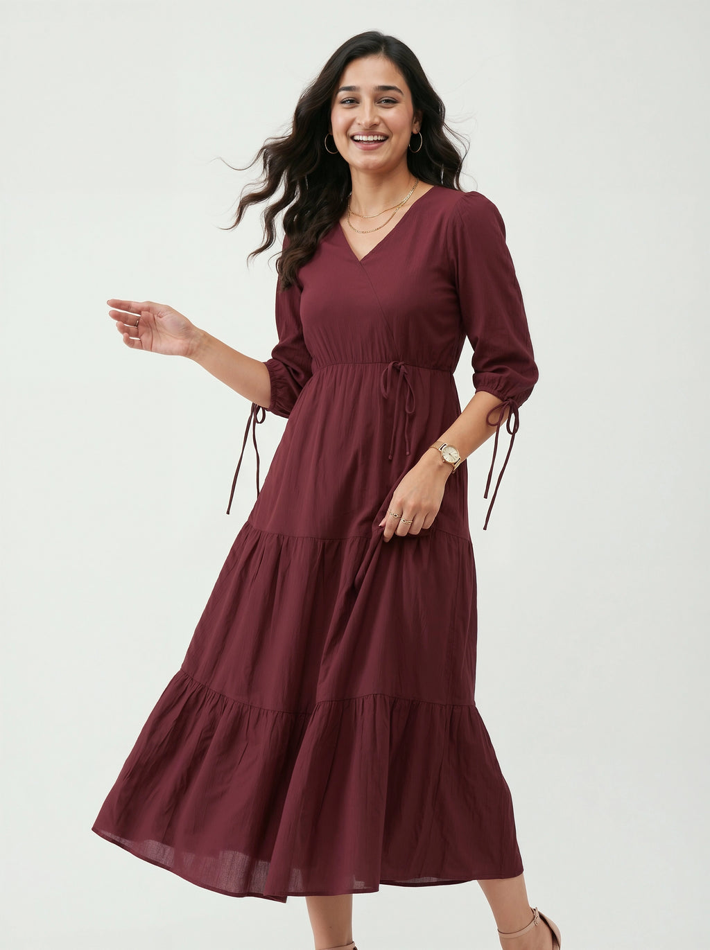 Woman wearing a burgundy dress with tiered skirt on a white background