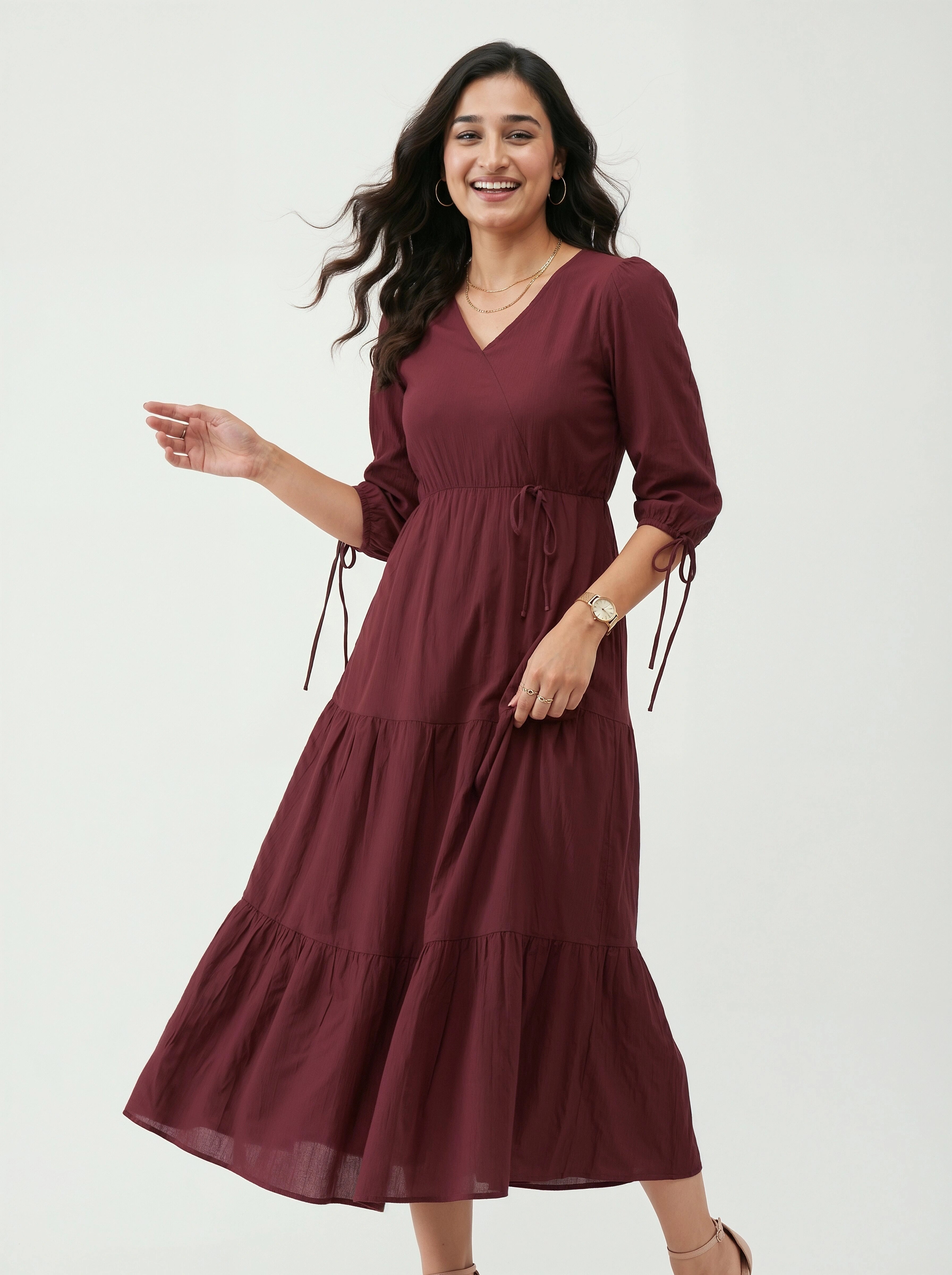 Woman wearing a burgundy dress with tiered skirt on a white background