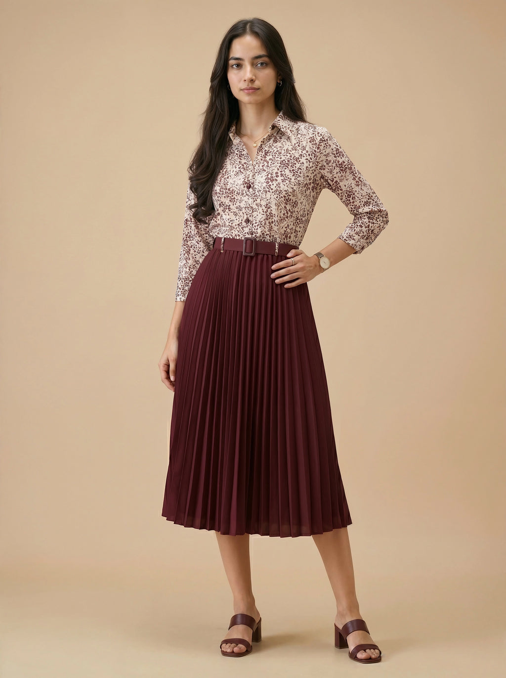Woman wearing a patterned blouse and pleated skirt on a beige background