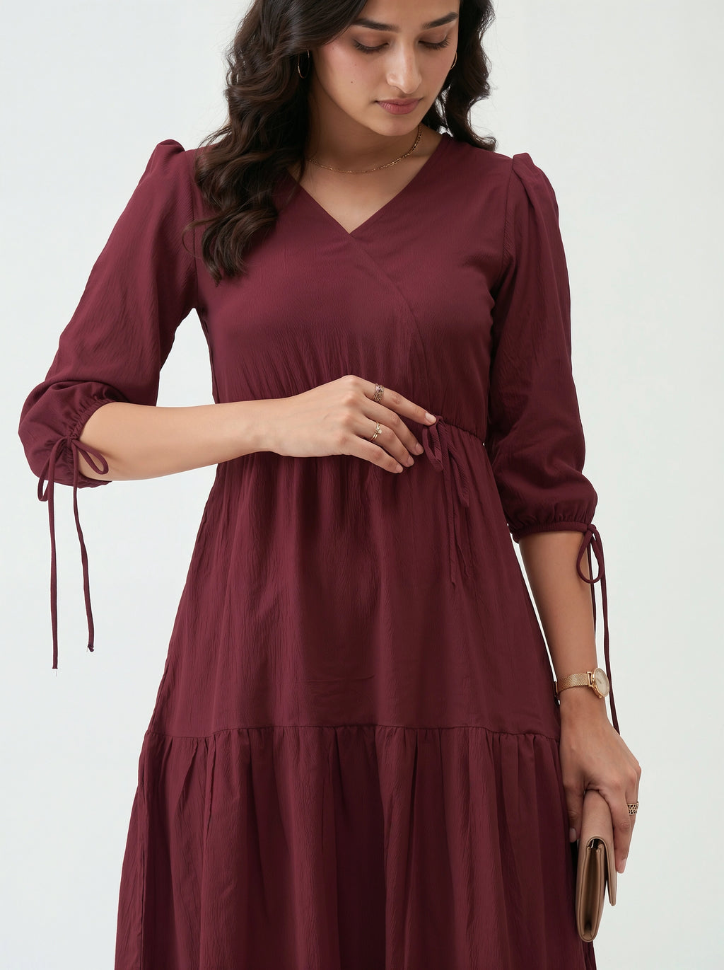 Woman wearing a maroon dress with long sleeves on a white background