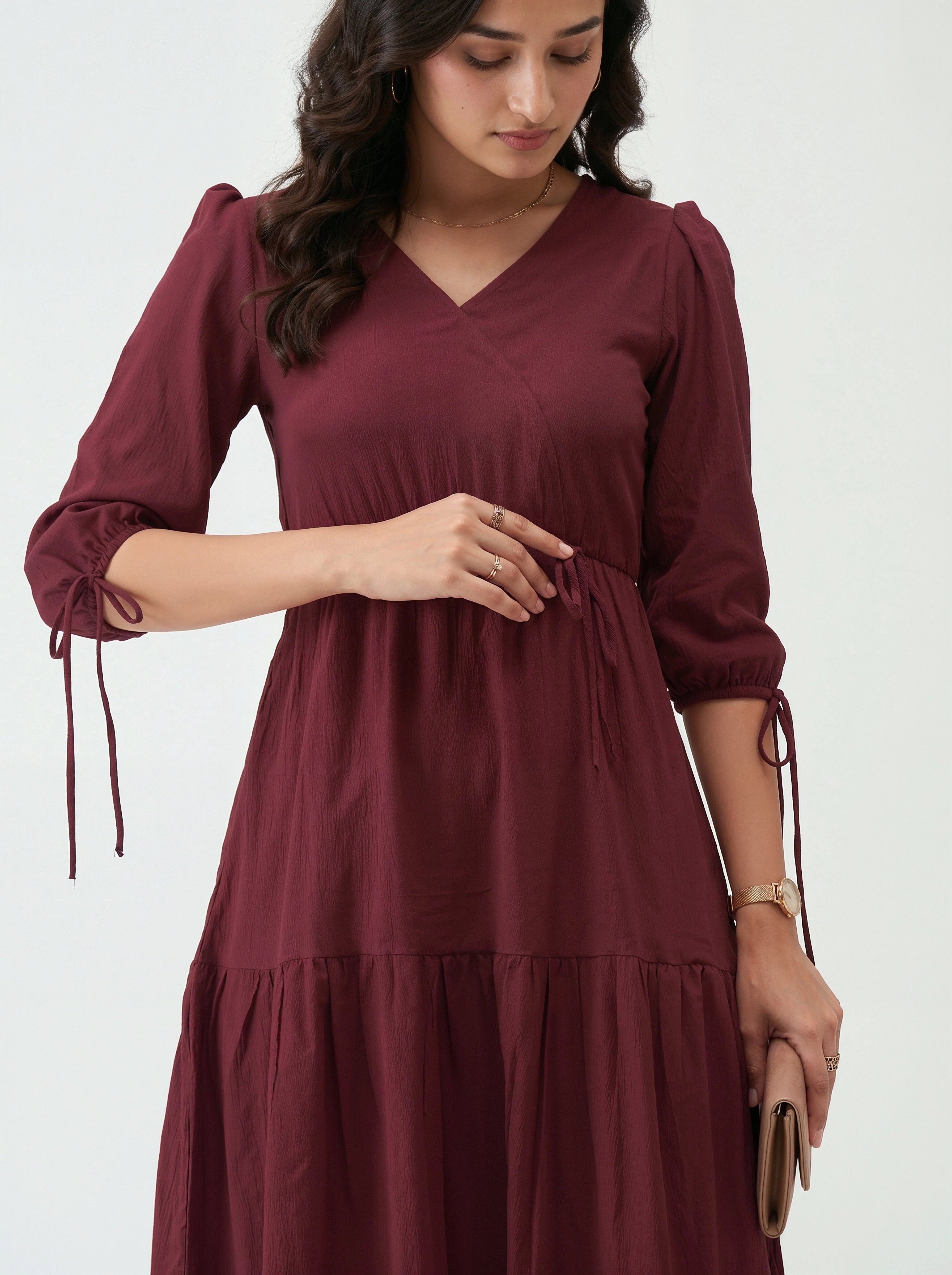 Woman wearing a maroon dress with long sleeves on a white background