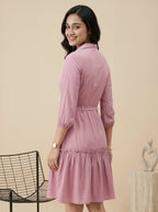 Woman wearing a pink dress standing against a beige background
