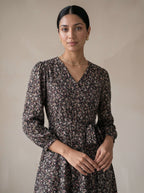 Woman wearing a floral dress against a plain background