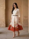 Woman wearing a white shirt and red skirt with floral patterns in an outdoor setting.