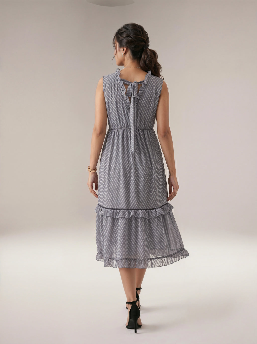 Woman wearing a gray patterned dress on a plain background