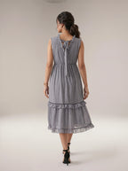 Woman wearing a gray patterned dress on a plain background