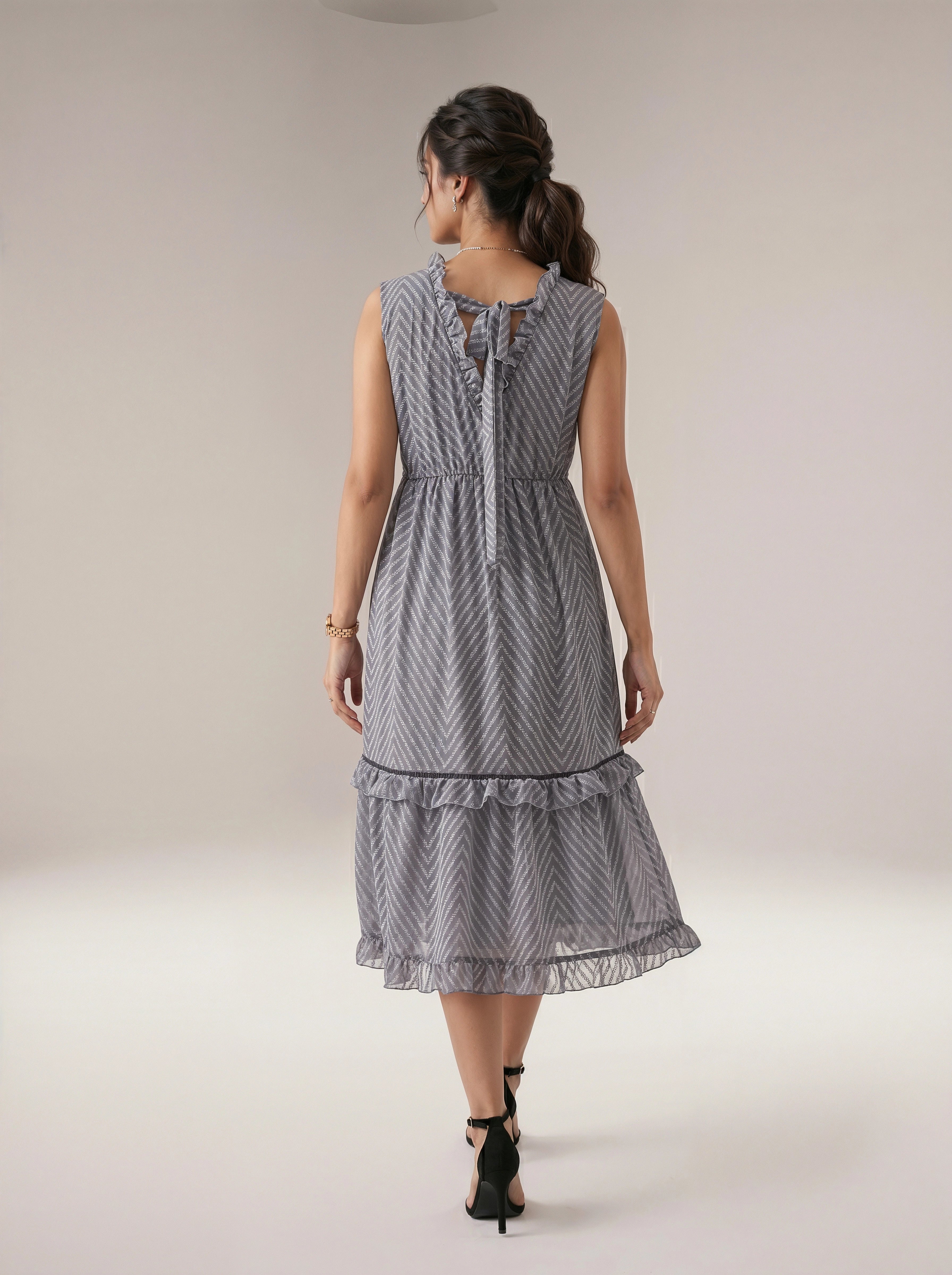 Woman wearing a gray patterned dress on a plain background