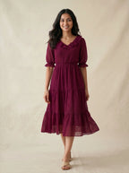 Woman wearing a burgundy dress against a beige background