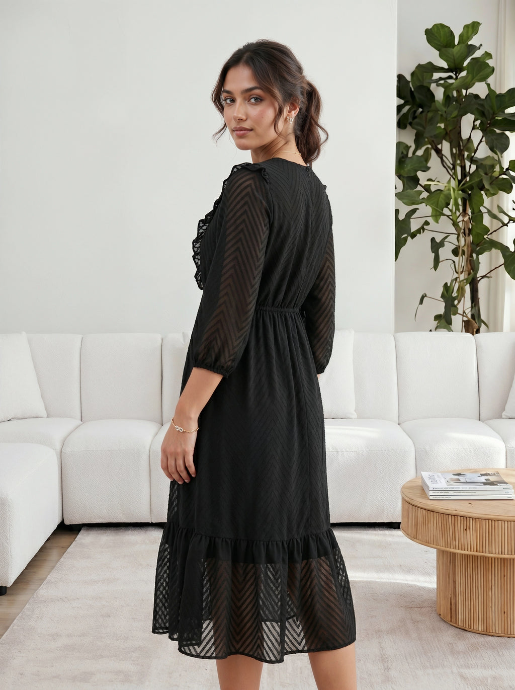 Woman in a black dress standing in a modern living room.