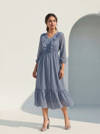 Woman wearing a blue dress standing against a light background