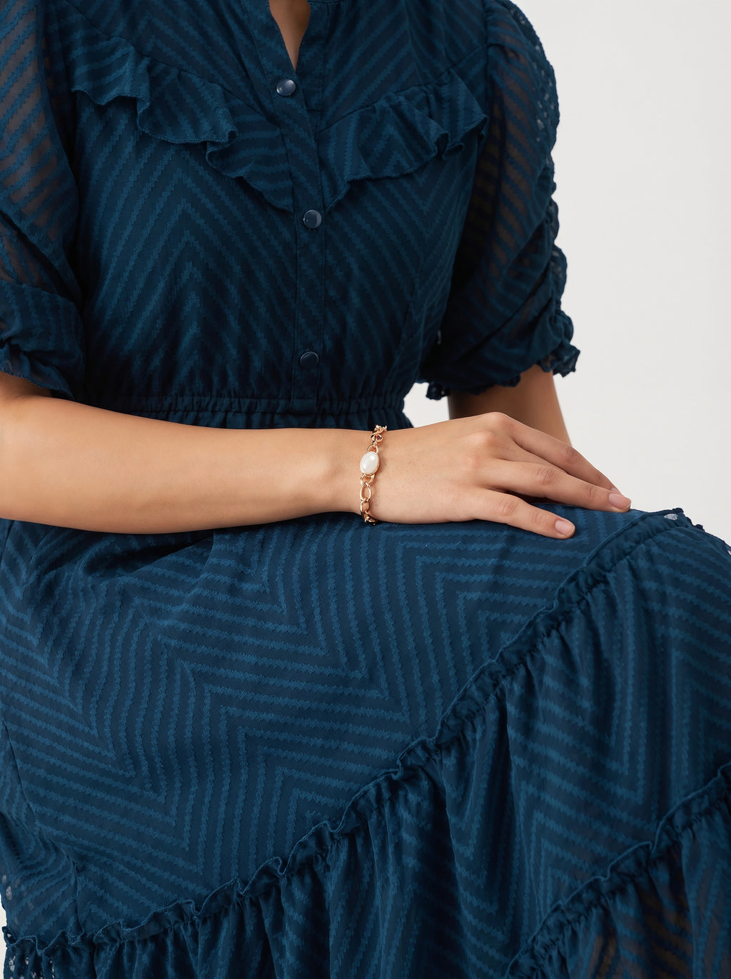 Woman wearing a dark blue dress with ruffled details on a light gray background