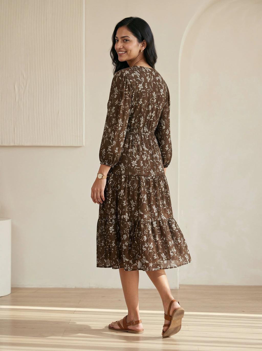 Woman wearing a brown floral dress in a minimal indoor setting