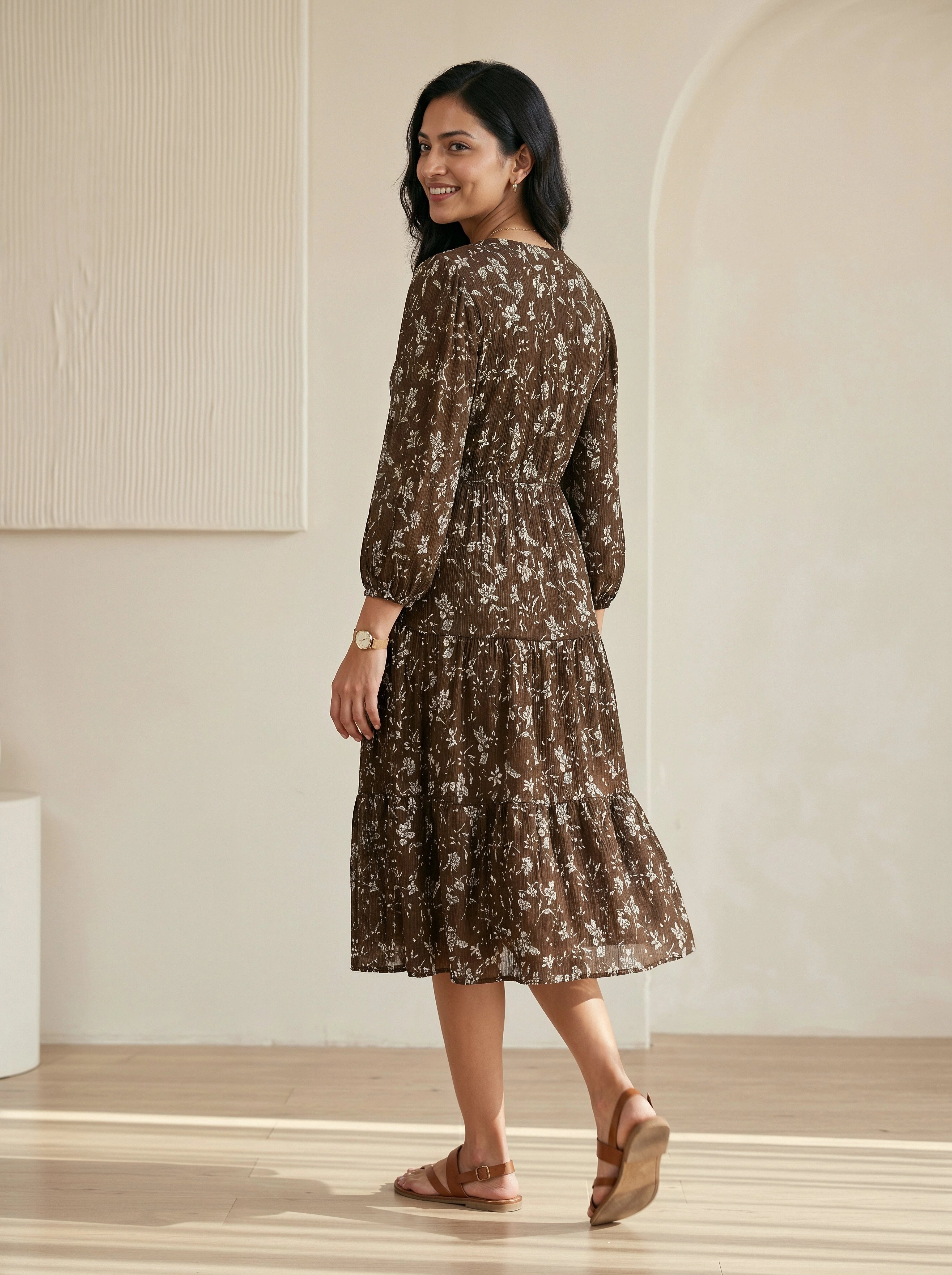 Woman wearing a brown floral dress in a minimal indoor setting