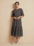 Woman wearing a black floral dress against a beige background