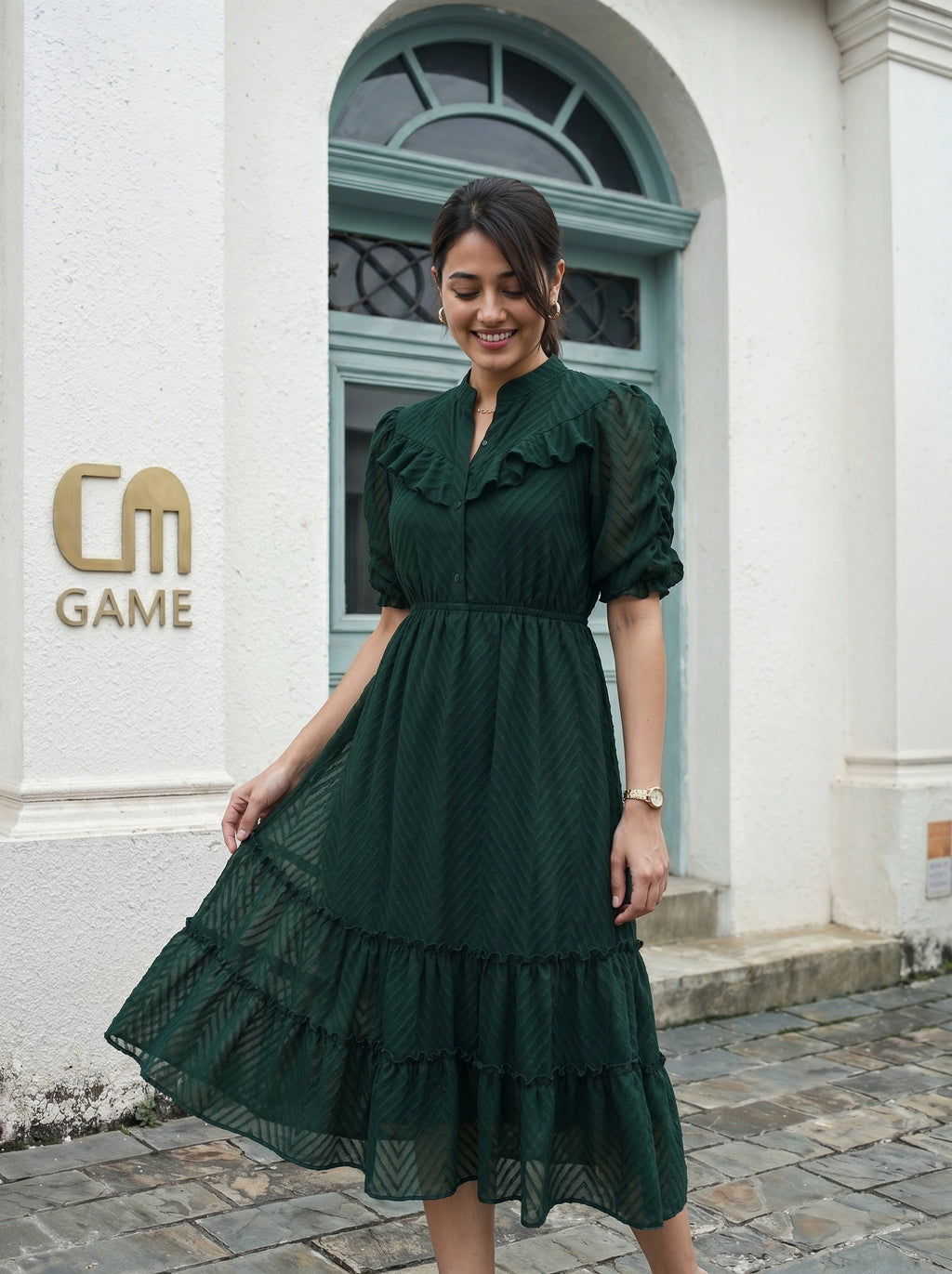 Woman in a green dress standing in front of a building with 'CM Game' logo.