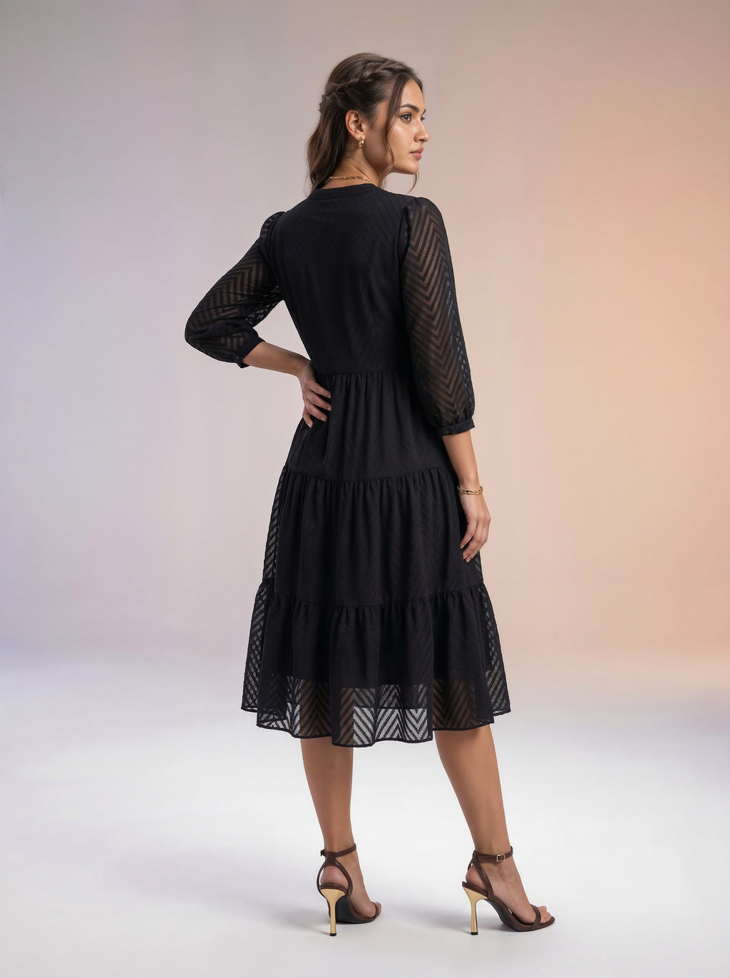 Woman wearing a black lace dress against a gradient background