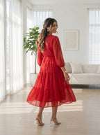 Woman in a red dress standing in a bright living room.