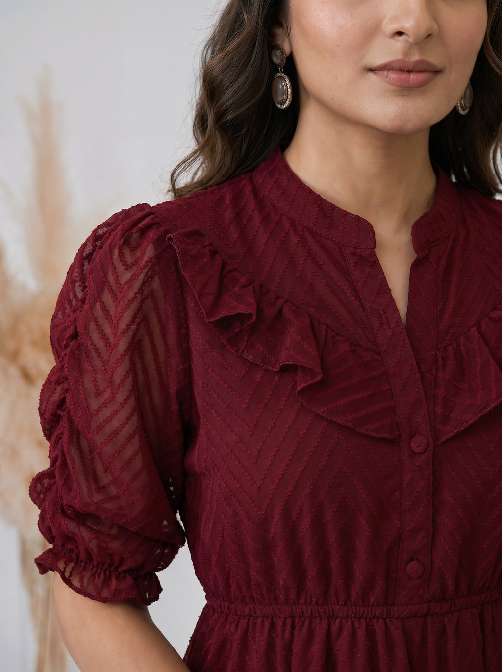 Woman posing in a textured maroon mid length dress with puff sleeves