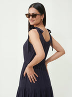 Woman wearing a navy blue dress with bow straps on a white background