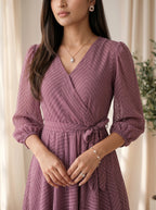 Woman wearing a purple patterned dress with a neutral background