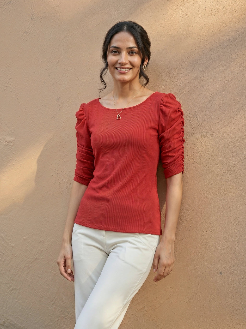 Woman wearing a red top with puffed sleeves against a beige wall