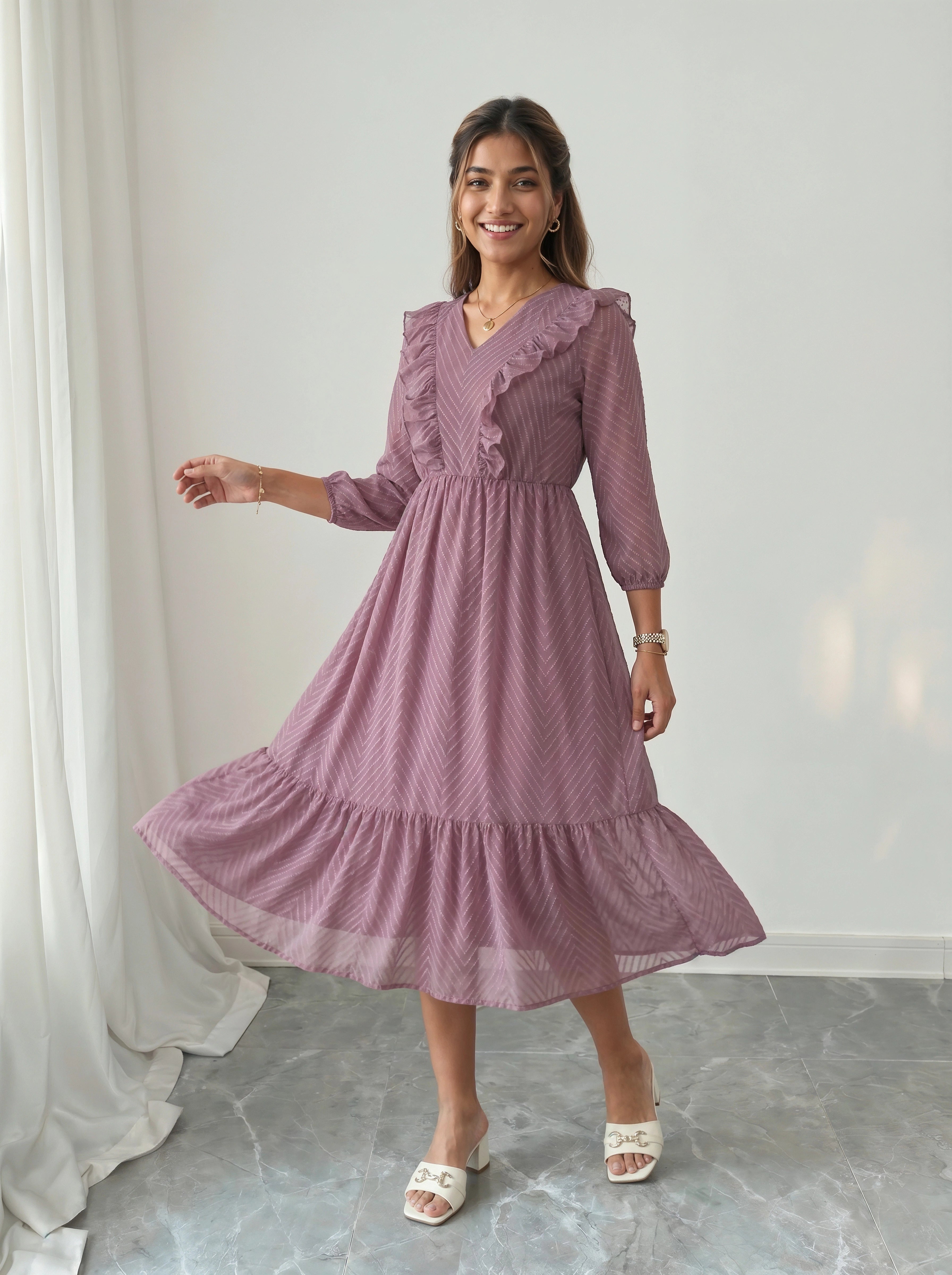 Woman wearing a purple dress standing in a room with white curtains and gray floor.