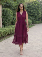 Woman in a burgundy dress walking on a path with greenery in the background