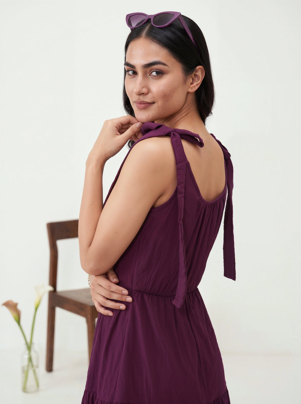 Woman wearing a purple dress with a chair and flowers in the background