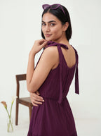 Woman wearing a purple dress with a chair and flowers in the background