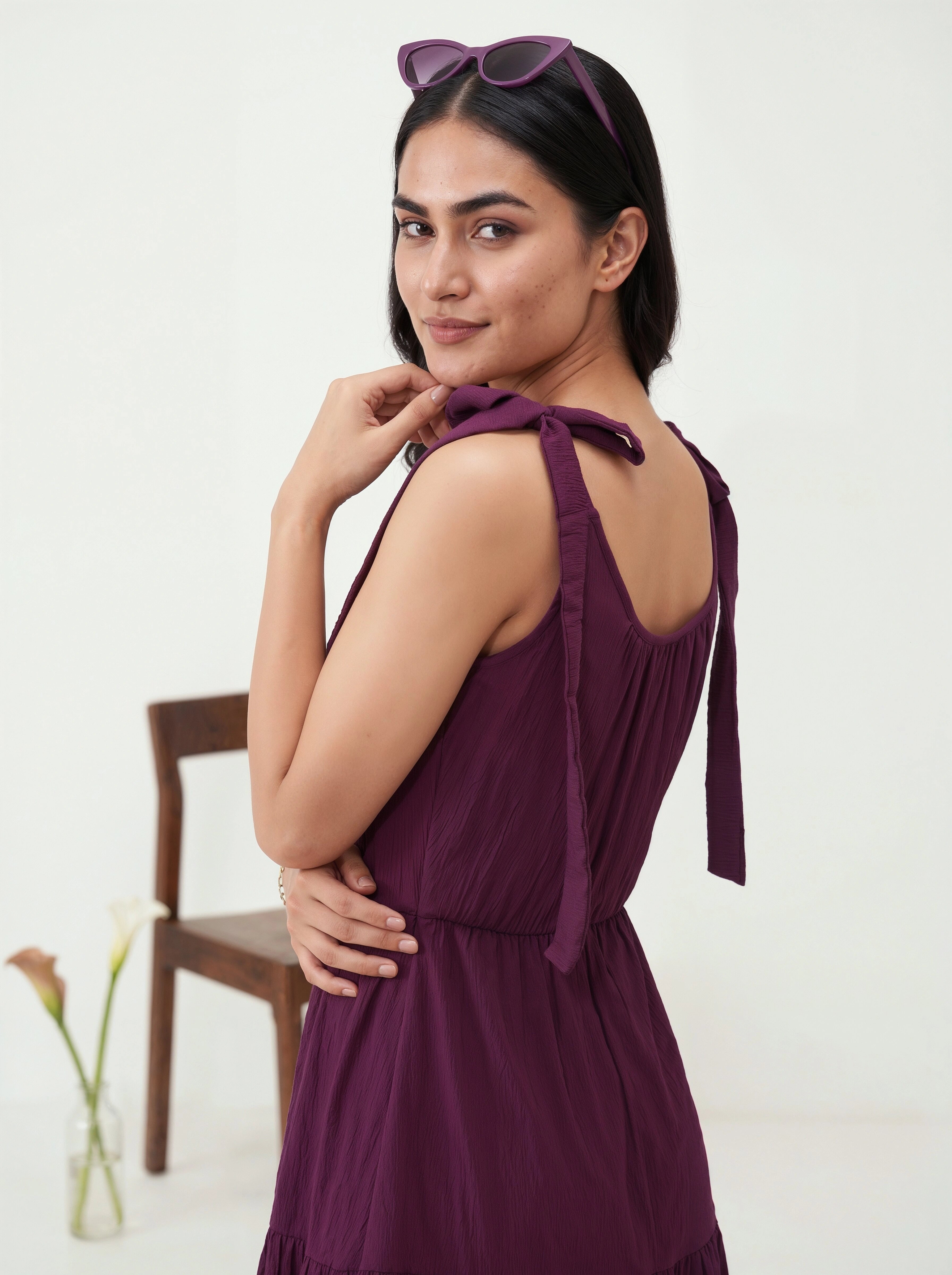Woman wearing a purple dress with a chair and flowers in the background