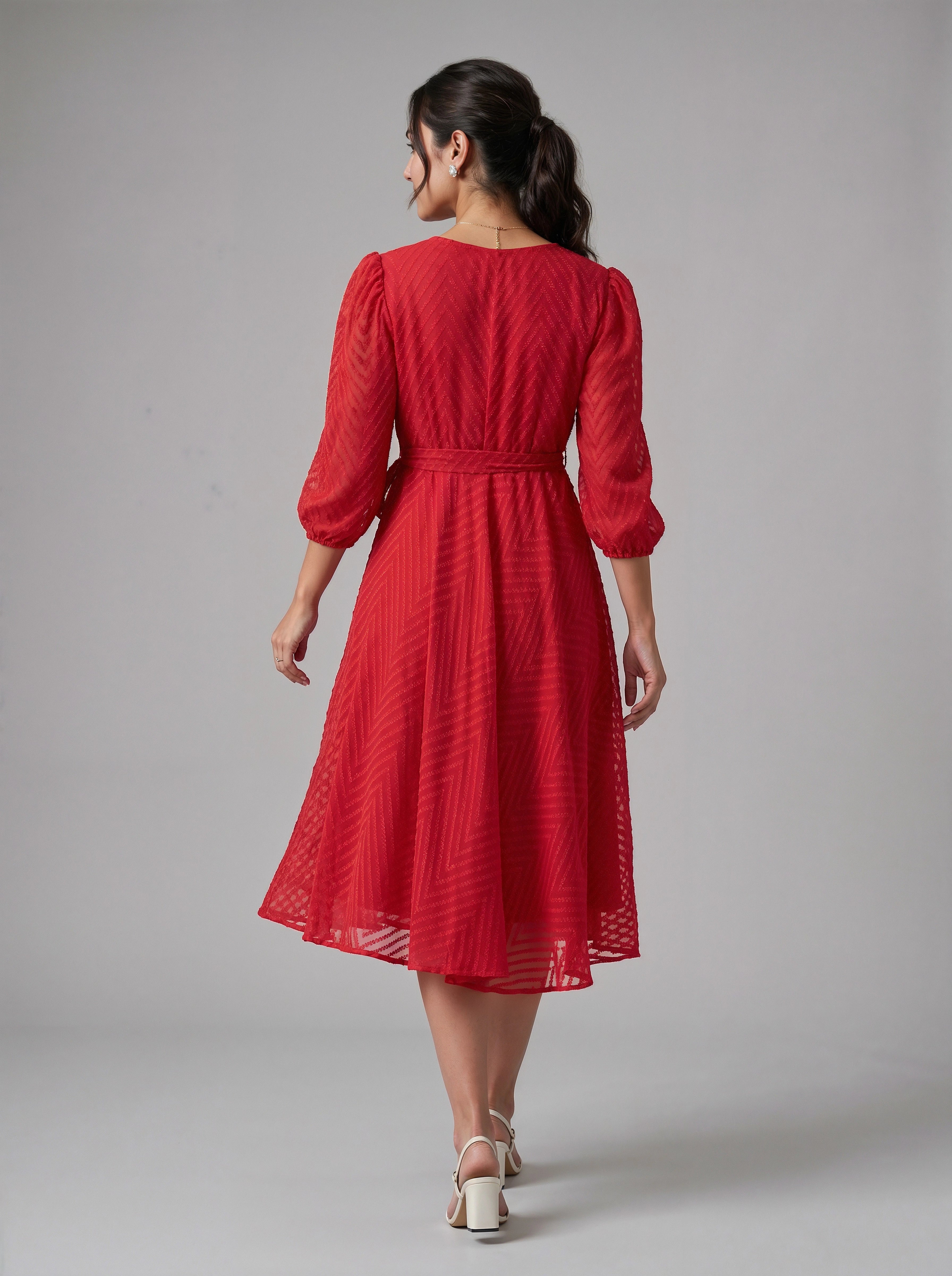Woman wearing a red dress with puff sleeves on a gray background