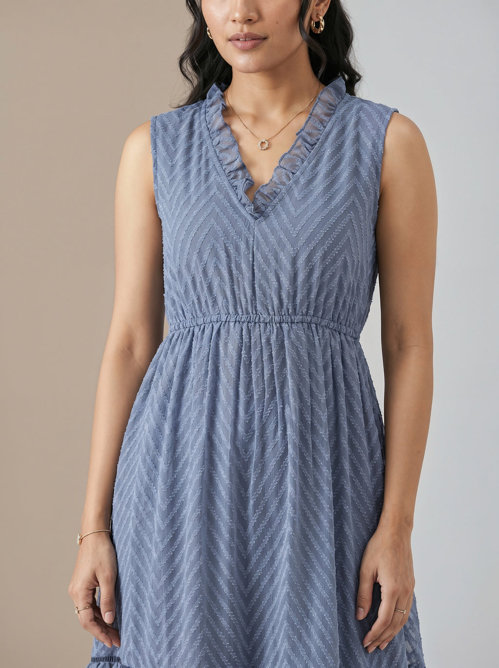Woman wearing a blue sleeveless dress against a neutral background